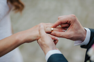 Obraz na płótnie Canvas the groom puts a wedding gold ring on the bride's finger