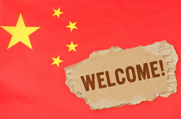 Against the background of the Chinese flag lies cardboard with the inscription - Welcome