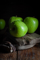 Green apples with water droplets on a wooden board in the dark style photo