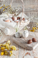 Easter basket with eggs and a bouquet of flowers, on a white wooden background.