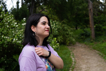 Fototapeta premium Photo of an attractive woman with black hair in the middle of nature during spring time, walking around and smiling during a sunny day