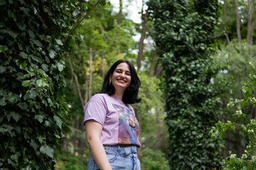 Fototapeta premium Photo of an attractive woman with black hair in the middle of nature during spring time, walking around and smiling during a sunny day