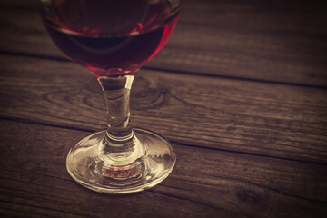 Glass of red wine on an old wooden table. Close up view