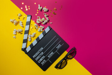 
movie clapper and popcorn on a yellow-pink background. flatley. copy space. cinema concept, cinema...