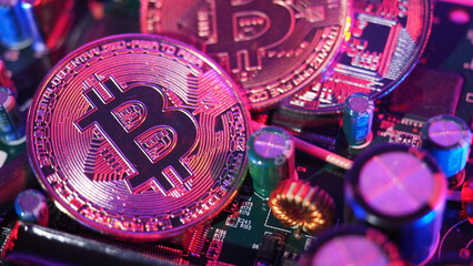 Cryptocurrency coins on circuit board. Bitcoins standing on CPU board. Close-up Bitcoin with blue and pink neon light. Printed circuit board with coin. Online Business money cryptocurrency concept. 