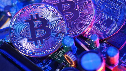Cryptocurrency coins on circuit board. Bitcoins standing on CPU board. Close-up Bitcoin with blue and pink neon light. Printed circuit board with coin. Online Business money cryptocurrency concept. 