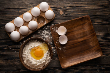 Eggs, flour and wooden dishes on a wooden table