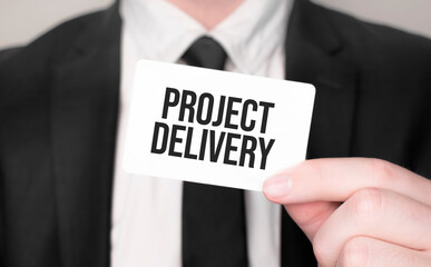 Businessman holding a card with text PROJECT DELIVERY
