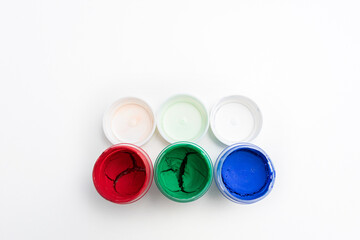 Set of jars of dry gouache paints, top view, close-up, white background, copy space