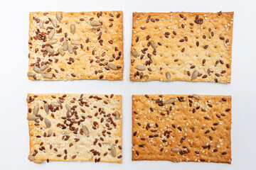 Square cookies with sesame seeds on a white background, top view
