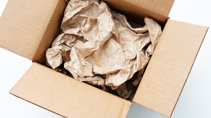 Brown cardboard box, crumpled yellow craft paper, white background, top view, cropped image, closeup, 16:9