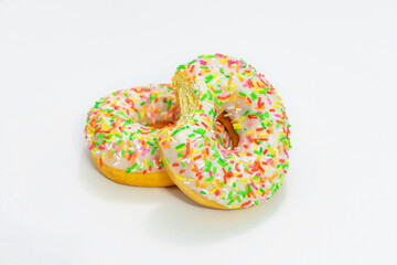 Two tasty donut with bright sprinkles, white background, side view, copy space