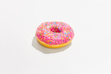 Pink donut with bright sprinkles, white background, side view, copy space
