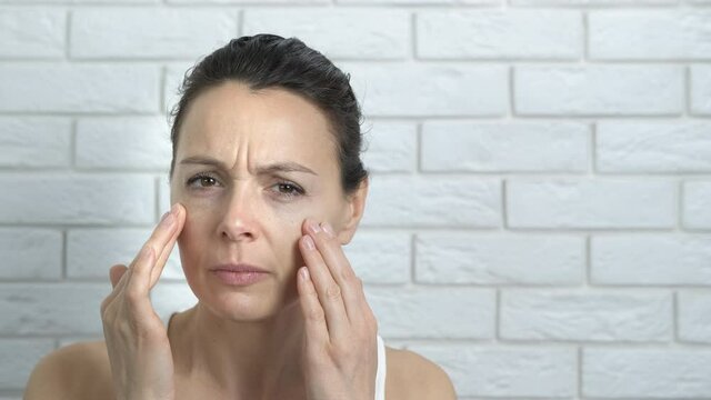 Dissatisfied of facial skin. A sad stressed woman has a facial problem and look with dissatisfaction on camera.