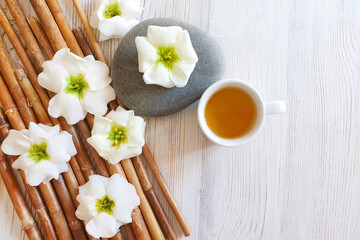 herbal tea in white cup, bamboo and flowers. Top view