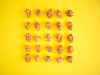 Hazelnuts on a neon yellow background. Hazelnut cube as a pattern. Pattern of peeled hazelnuts. Illuminating yellow background in hazel properly arranged. Hazelnut cube shape. 