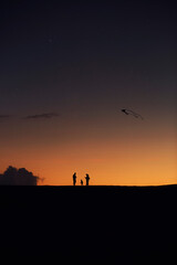 Familie Silhouetten Schatten bei Nacht in der Wüste am Strand mit orangen farben am dunklen Himmel
