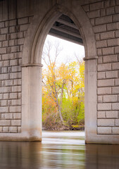 The view under a concrete bridge.  Stone like arches with the Mississippi river flowing smoothly...