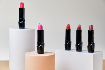 Set of open lipsticks on trendy pedestals, unbranded presentation of cosmetics