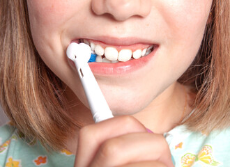 Vista de la boca de una niña cepillándose los dientes con un cepillo de dientes eléctrico sin...