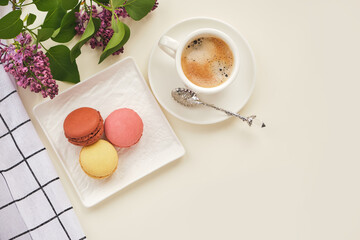 Cup of coffee with macaroons on a table with flowers