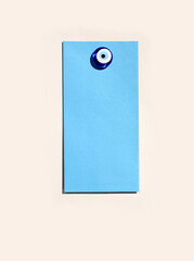 Blue envelope mock-up on magnetic board with glass evil eye magnet