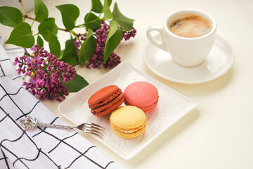 Cup of coffee with macaroons on a table with flowers