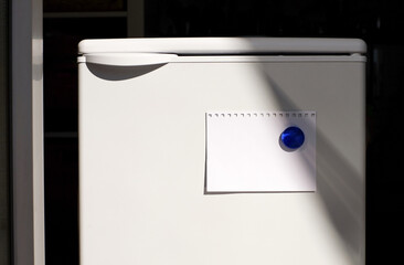Note paper on fridge with glass magnet, sunlight, copy space
