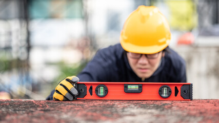 Asian maintenance worker man holding red aluminium spirit level tool or bubble levels at...