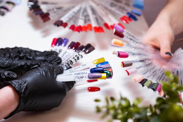 Obraz premium Master with a customer in beauty salon choose the color of gel in manicure and pedicure cabinet. Set of different nail polish colours on multicolor nail polish palette for client choice. Nail art 