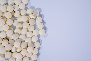 Herbal pills with healthy medical plant on gray background. Close up of compressed pills from herb powder, alternative medicine. Copy space