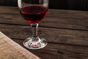 Glass of red wine and piece of canvas on an old wooden table. Angle view