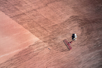 Tractor with a harrow in the field. Shooting from a drone. Copy space.