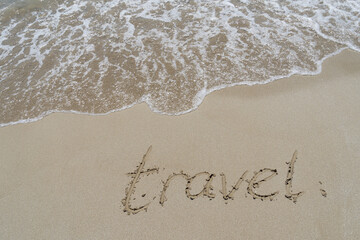Fototapeta premium travel written in fine sand on the beach