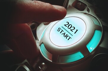 Finger about to press a car ignition button with the text 2021 start. Year two thousand and twenty...