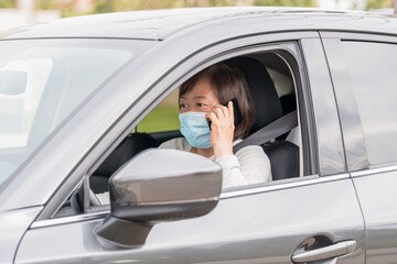 Mature asian woman in a car talking on her phone: Selective focus.