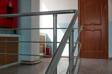 staircase of an office space with door, tiled floor and stainless railing