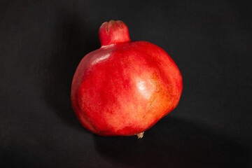 single pomegranate on black background