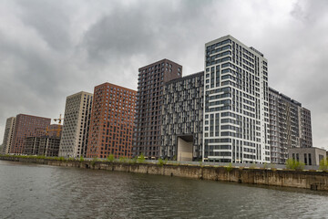 Obraz premium Residential buildings on the banks of Moskva River on a cloudy day. Housing construction according to the city renovation program. Moscow, Russia