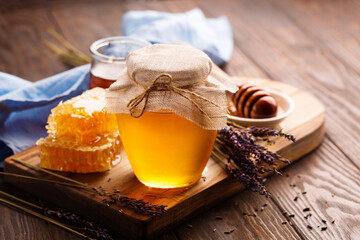 Jar of liquid honey with honeycomb and bunch of dry lavender
