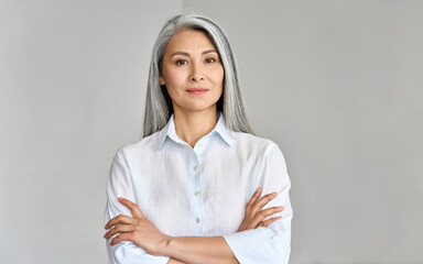 Stylish confident adult 50 years old Asian female psychologist standing arms crossed looking at...
