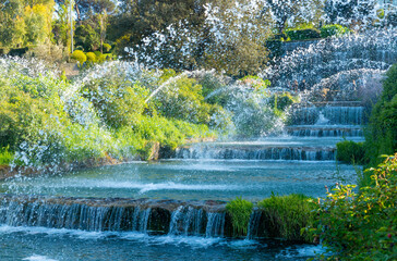 Naklejka premium Waterfalls of the pond in the Eur district in the center of Rome. Beautiful reflections of the water on a spring day with blue sky. Rome Eur, Italy.