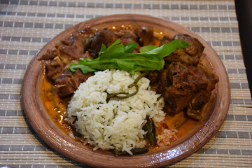 Close-up of lamb tandoori  and rice on a ceramic plate . Traditional Aegean kitchen