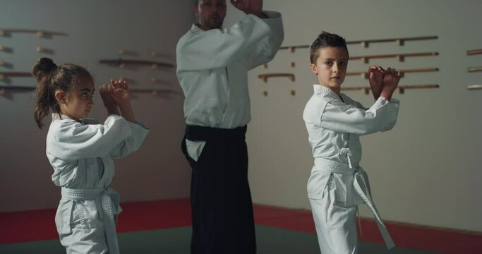 Cinematic shot of budokai fighter master and his pupils practicing Aikido training in modern Japanese martial arts school. Concept of healthy lifestyle, sports, recreation, defence, religious beliefs.