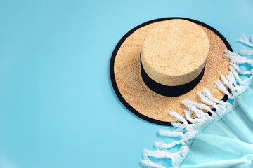 Fototapeta na wymiar Straw hat and towel on a blue background. Summer concept.