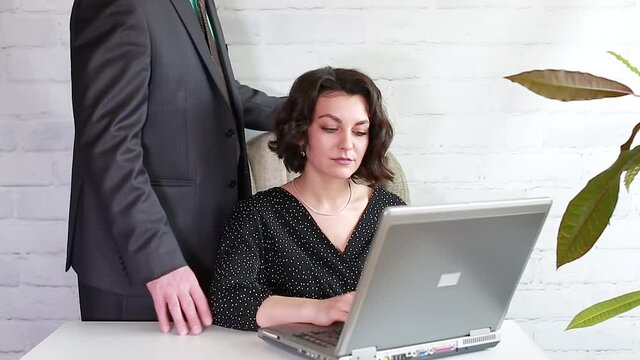 A male boss touches a female colleague with his hands at the workplace The Boss Is Harassing His Secretary Office harassment. 