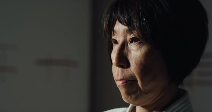 Cinematic macro of mature female fighter with kimono concentrating before practicing Aikido in martial arts school. Concept: healthy lifestyle, sports, recreation, defense, religious beliefs