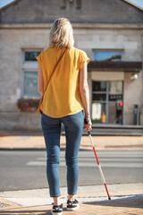 blind woman with a cane crossing the street
