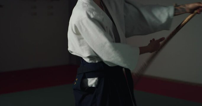 Cinematic shot of budokai fighter master practicing with wooden sword Aikido training in modern Japanese martial arts school. Concept of sports and recreation, philosophy, defense, religious beliefs.