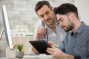 teacher in computing class assisting teenager with tablet